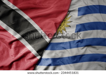 big waving realistic national colorful flag of trinidad and tobago and national flag of uruguay. macro