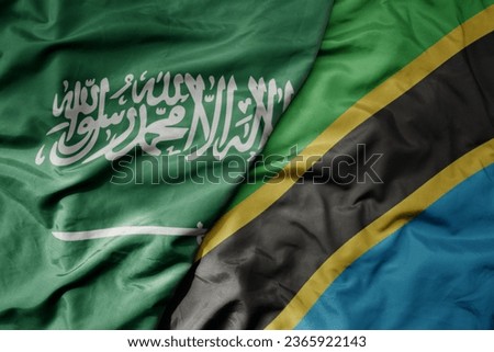 big waving realistic national colorful flag of saudi arabia and national flag of tanzania . macro