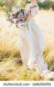 big wedding bouquet in hands of the bride, modern bouquet with a silk ribbons for the bride, summer stylish floristry, the bride in a beige dress holds the flowers