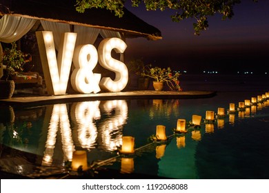Big wedding light up letters V & S near the pool with reflection on the water. Festivity, wedding, party. 