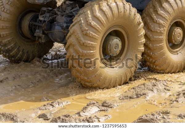 big wheels in the mud. The large wheels of a truck\
stuck in the mud.
