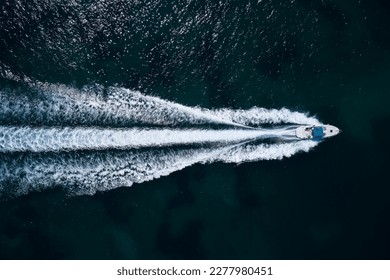 Big white boat with a blue awning fast movement on dark water top view. - Powered by Shutterstock