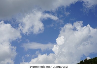 Big White Clouds On Blue Sky. Clouds And Variable Weather In The Mountains Seen From Below.