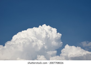 Big White Fluffy Clouds On Clear Blue Sky. Cloudy Sky Background With Copy Space. Cumulus Cloud Close Up