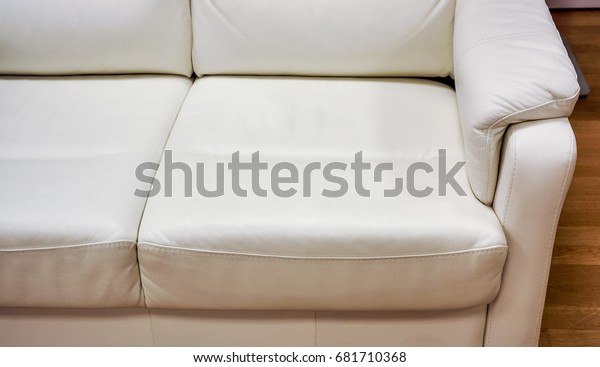 big white lather soft sofa\
divided into three sections for comfortable waiting on reception or\
in waiting room in big office. close up of white sofa in a waiting\
room