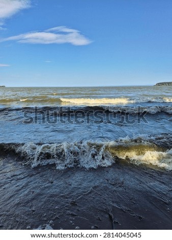 Big White River Waves Rolling onto a Sandy Shore in Sunny Windy Weather