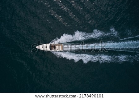 Big white speedboat fast movement on dark water top view. Speedboat with people on the water top view.