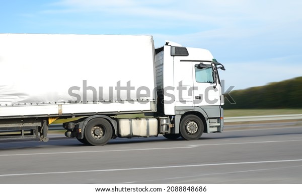 big white truck on\
the highway - freight transport concept, beautiful sky, clean and\
empty space - side view