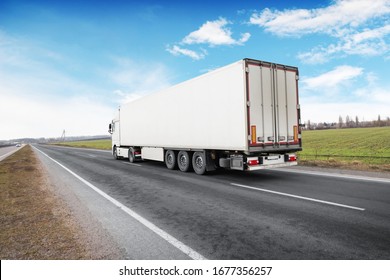 A Big White Truck And A Trailer With Space For Text On The Countryside Road Against A Blue Sky With Clouds