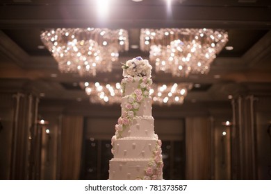 Big White Wedding Cake In Ballroom Hall Decoration With Flower Cream In Vintage Color Tone 