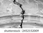 Big winding crack in arched structure, abstract image of vertical cleft. Black and white photo. Close-up. Copy space. Selective focus.