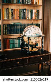 Big Wooden Vintage Globe In A Table Near Bookshelf In Library.