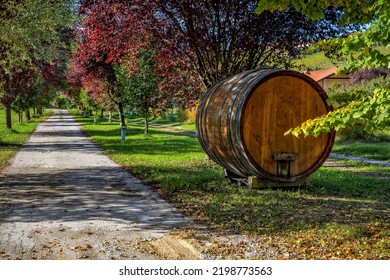 Big Wooden Wine Barrel On The Side Of The Narrow Rural Road Among The Trees In Piedmont, Northern Italy.