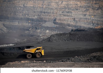 Big yellow mining truck hauling rock in dusty coal mine 
