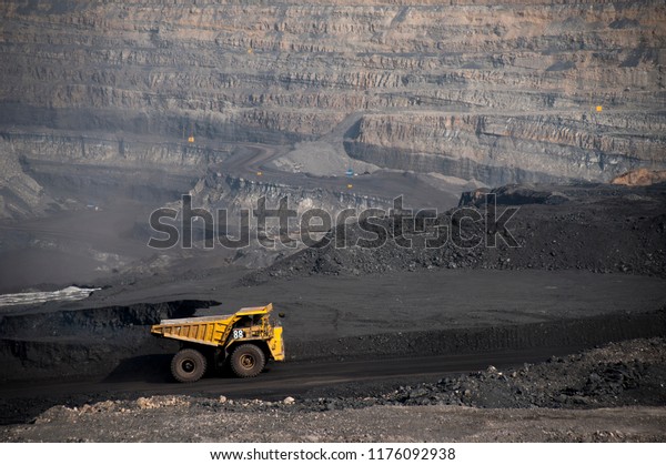 Big\
yellow mining truck hauling rock in dusty coal mine\
