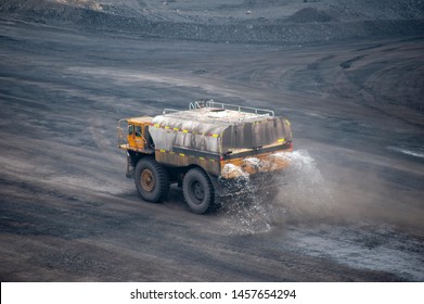 Big Yellow Mining Truck Sprays Water Onto A Dusty Coal Mine Road In China