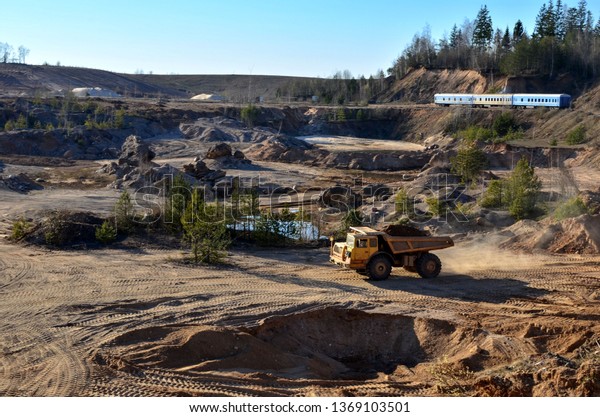 Big yellow mining truck transporting\
sand in an open-pit mining quarry, top view -\
image