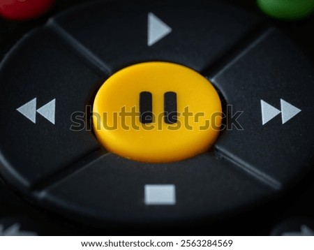 A big yellow pause button on a TV remote.