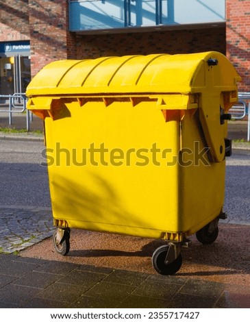 Big yellow trash can stayed on the street.