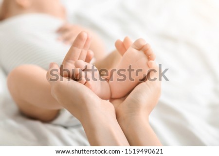 Biggest treasure in the world. Mother holding tiny feet of her newborn baby in hands