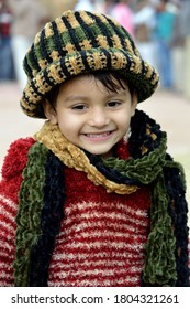 Bikaner, Rajasthan / India - January 13,2017: A small beautiful girl, wearing a sweater and a woolen cap, plays at the Karni Singh Stadium Bikaner at the Camel Fair.