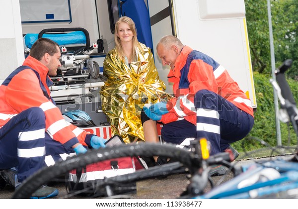 Bike accident woman emergency doctor bandage leg\
in ambulance smiling