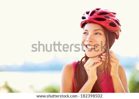 Bike helmet - woman putting biking helmet on outside during bicycle ride.