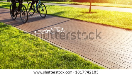 Bike lane in the city public park. Two cyclists ride the bike path early in the morning. Healthcare and active lifestyle.