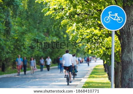 Bike lane, bike path sign in summer green park. Cyclists on bicycles and pedestrians. Concept of rest and relaxation, exercise, healthy lifestyle