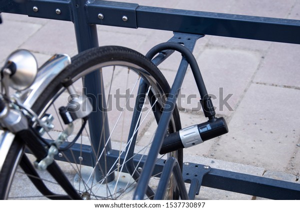 Bike locked\
securely via u-lock in bicycle parking area. Back right side view\
of front wheel. Security, stolen\
bike