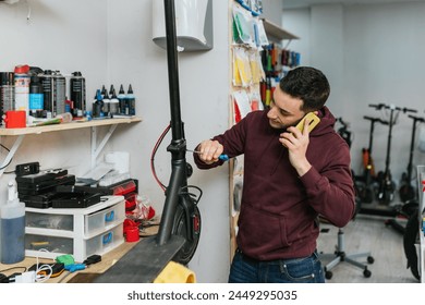 The bike mechanic attends a call while repairing an electric scooter with a screwdriver. - Powered by Shutterstock