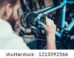 Bike Mechanic Repairs Bicycle in Workshop. Closeup Portrait of Young Blurred Man Examines and Fixes Modern Cycle Transmission System. Bike Maintenance and Sport Shop Concept