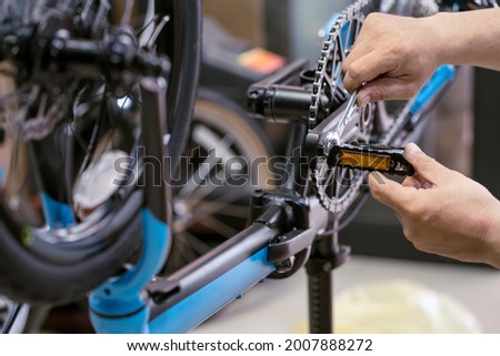 Bike mechanic repairs folding bicycle in Workshop. adjust Bike Pedals . Bicycle Maintenance and Repair concept