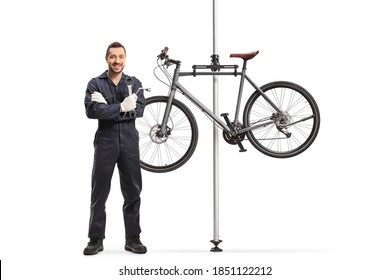 Bike mechanic standing next to a bicycle hanging on a stand isolated on white background - Powered by Shutterstock