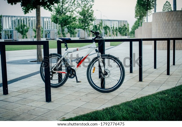the bike is parked in a bike Park and tied up in the\
background of the Park
