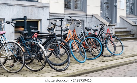 Bike parking in the city. Bicycle parking along a street near a city building in Amsterdam. An urban cityscape with bicycles. Walking bikes parked casually along an old street in Netherlands. 