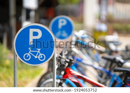 Bike parking sign with a blurred bicycle background.