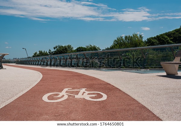 Bike path with of bicycle\
symbol. Pink bike lane with non-slip acrylic coating on city\
footbridge