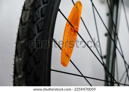 Bike reflector. A simple orange plastic cataphote on a bicycle wheel. Safe driving in the dark.