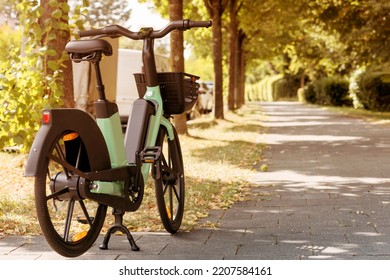 Bike Rent E-bicycle In Park Street. Electric Bicycle Sharing Service. Electric Bike In Urban Space Background.