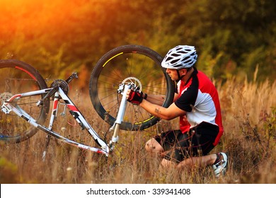 Bike Repair. Young Man Repairing Mountain Bike In The Forest