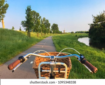 Bike Rides Along The Bike Path Towards The Mill. Typical Dutch Landscape. Bicycles And Mills Are Symbols Of The Netherlands. Environmental Protection Transport.