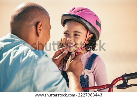 Bike safety, kid and helmet of a girl with father ready for cycling learning outdoor with a smile. Dad with happy kid putting on safe gear for a bicycle teaching lesson with happiness and care