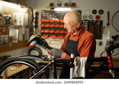 Bike service, repair and upgrade concept. Cycling mechanic fixing bicycle seat in workshop or garage. Old caucasian repairman. Copy space - Powered by Shutterstock