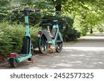 Bike Sharing System and Scooter Rental Service in Green City. e-bicycle e-scooter parked in Sidewalk. Eco Transport concept. Green Background. Copy Space