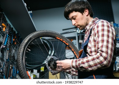 Bike shop mechanic fixing bicycle wheel in workshop. Serviceman repair, maintenance cycle. Velocipede repairing bicycle in bike shop. Bicycle repair service concept. Environmentally friendly vehicles. - Powered by Shutterstock