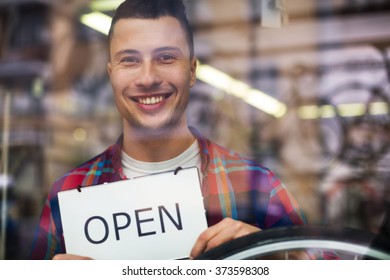 Bike Shop Owner Holding Open Sign
