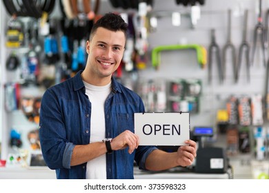 Bike Shop Owner Holding Open Sign
