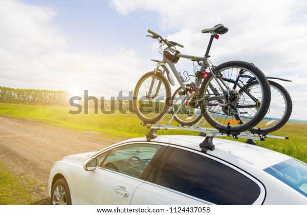 Bike transportation - two bikes on the roof of a car\
against a beautiful sky. the end of the transportation of large\
loads and travel by car