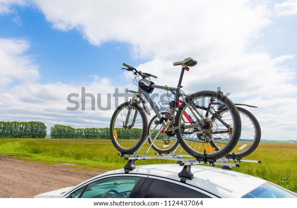 Bike transportation - two bikes on the roof of a car\
against a beautiful sky. the end of the transportation of large\
loads and travel by car
